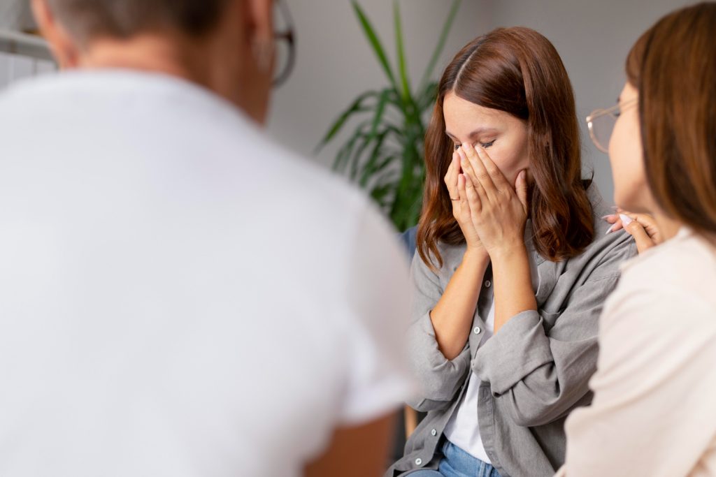 person becoming emotional during a therapy session, supported by others in a group setting, reflecting how an intensive outpatient program can fit into everyday life without disruption