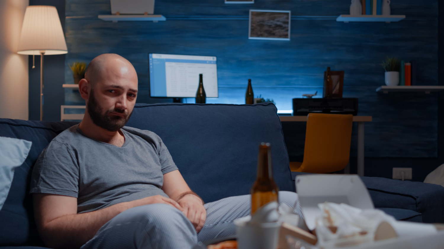 individual sitting alone with alcohol while experiencing anxiety relapse during addiction recovery
